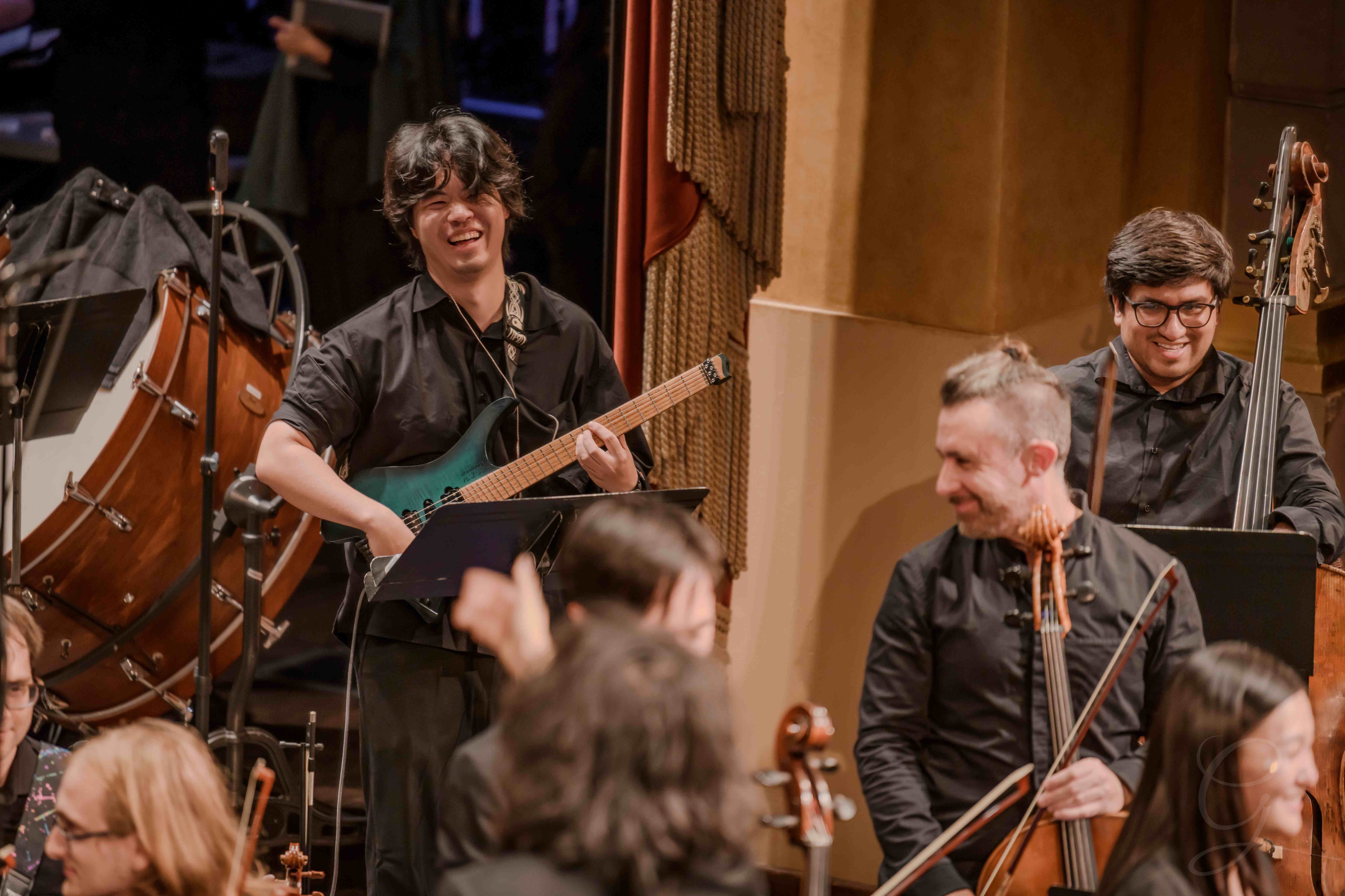 Bassist smiling while performing on electric bass with the ensemble