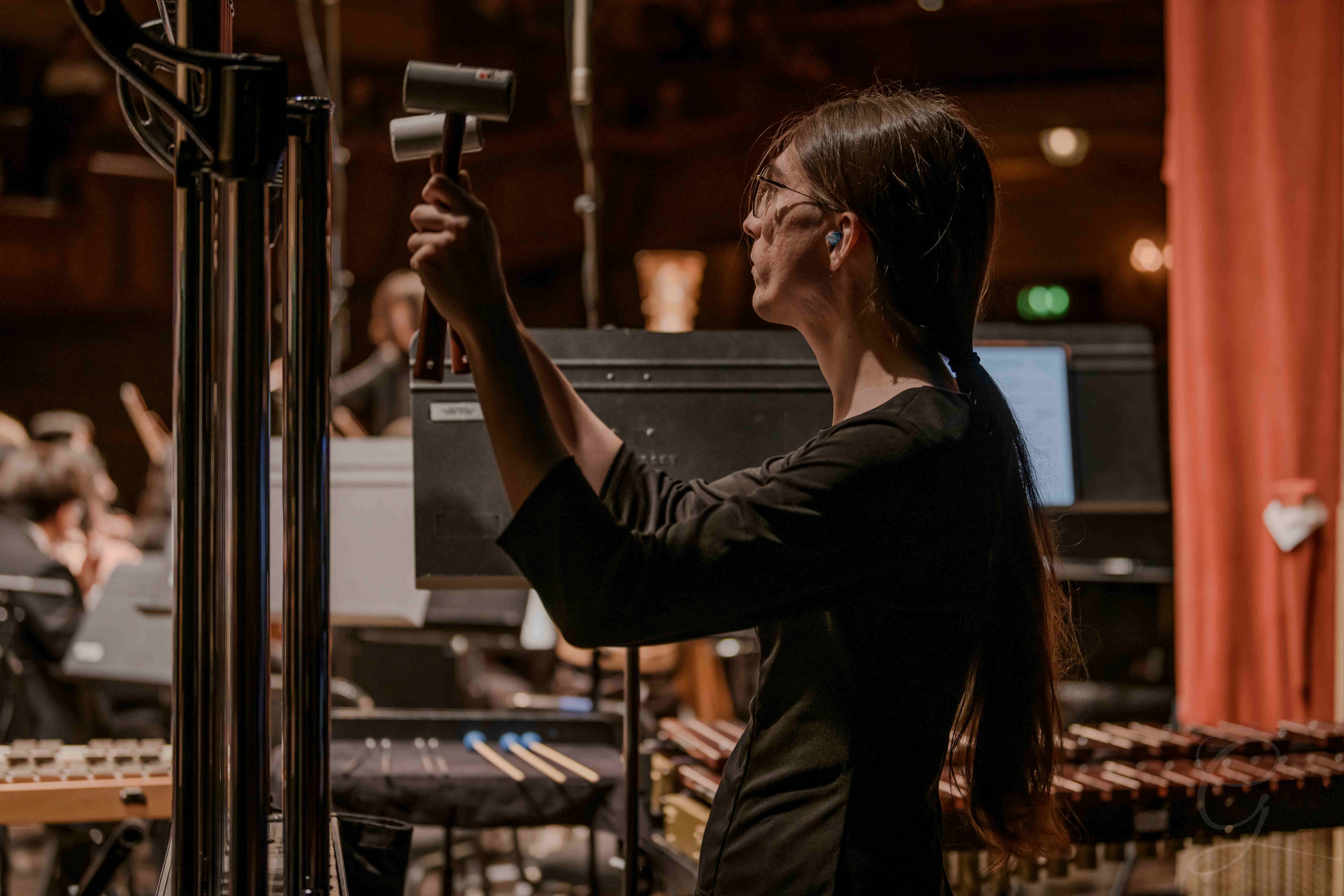 Percussionist raising a mallet to play the chimes during a GG Orchestra concert