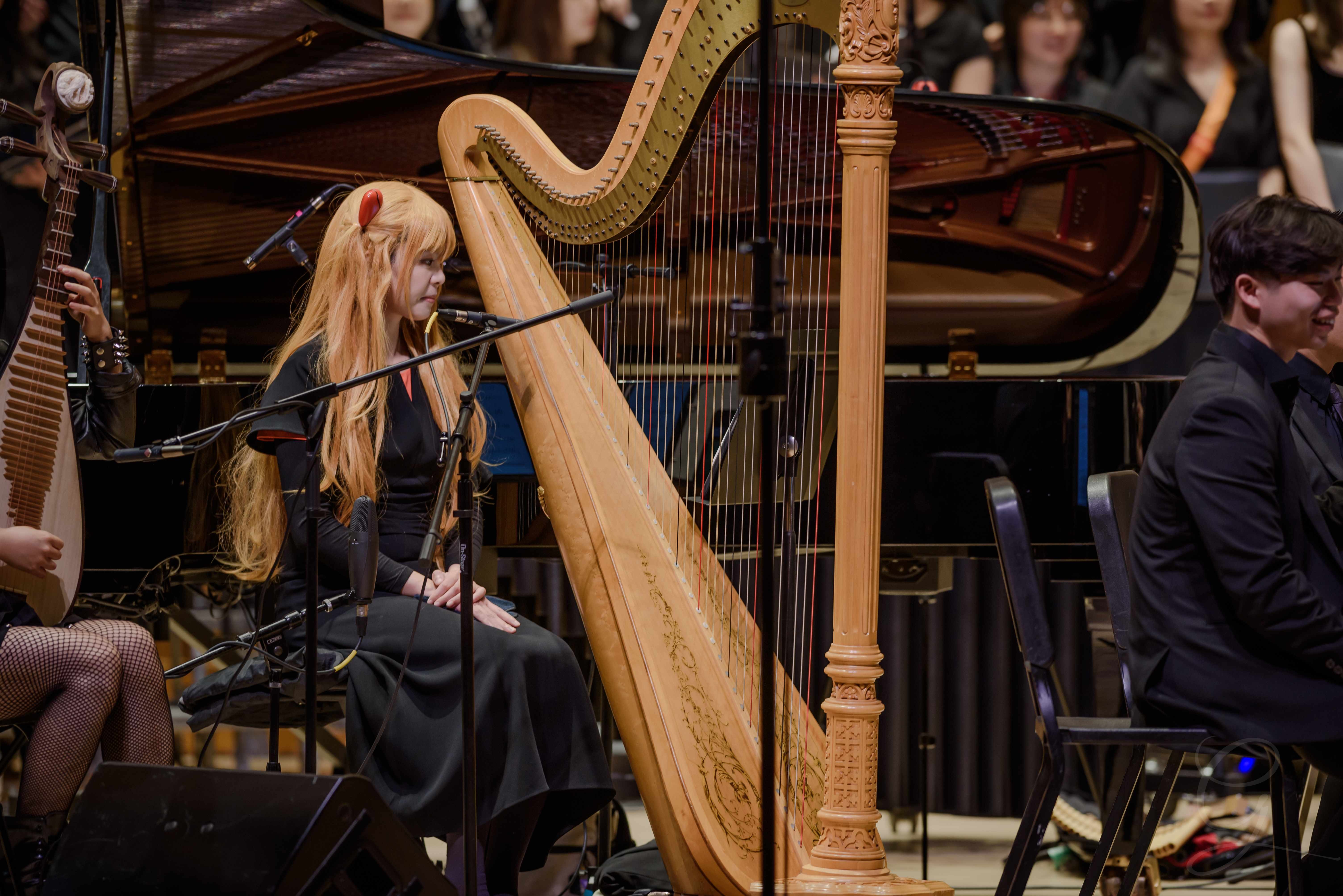 Vocalist performing beside an ornate harp and grand piano on stage