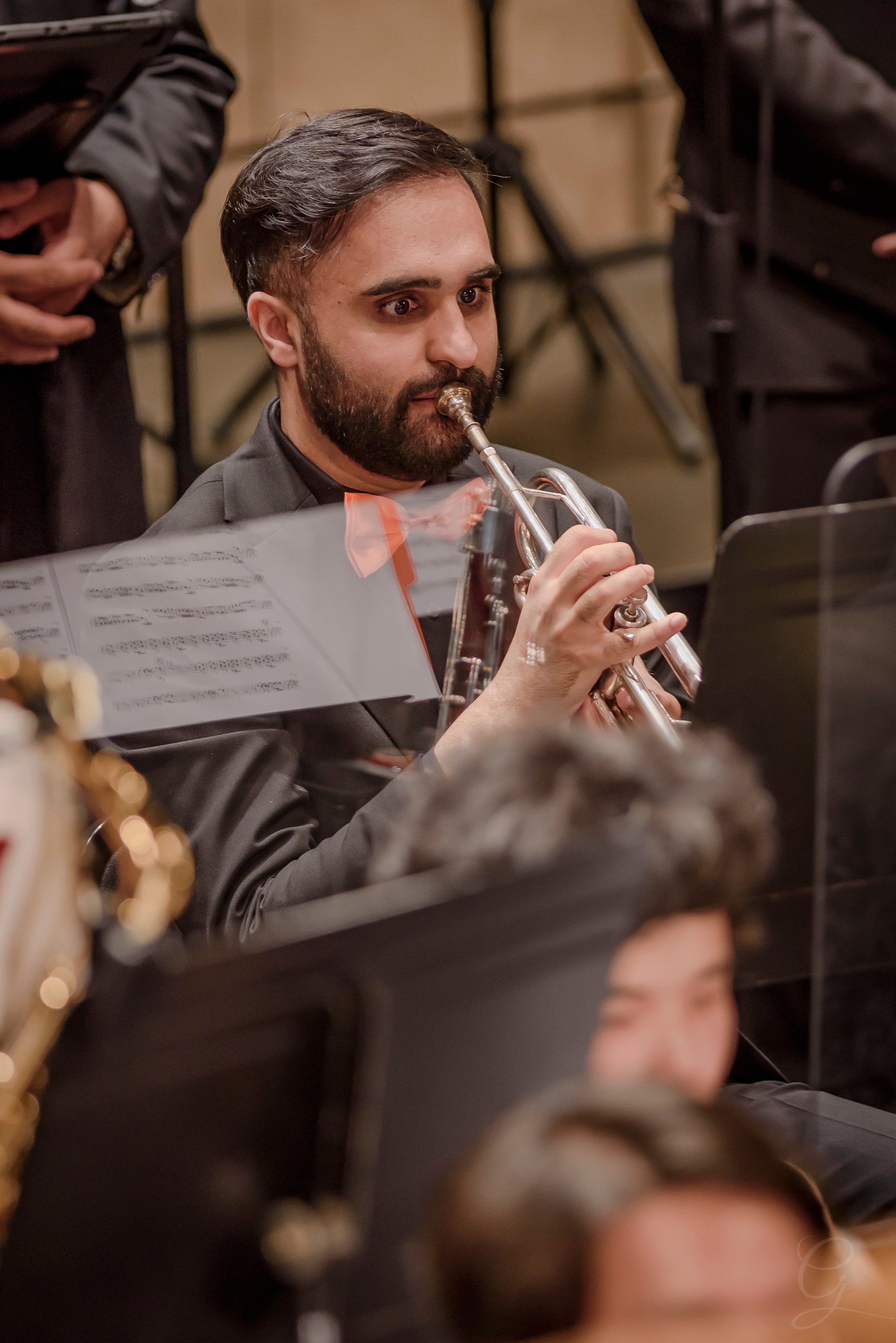 Trumpet player in an orange bow tie performing with the brass section